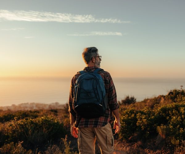 Mature,Backpacker,Looking,At,The,Panoramic,View,On,A,Hilltop.